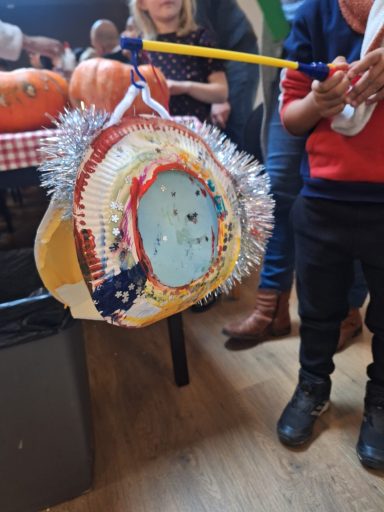 Kleurrijke feesthoed versierd met glitter en pompoenen, gedragen door een kind.